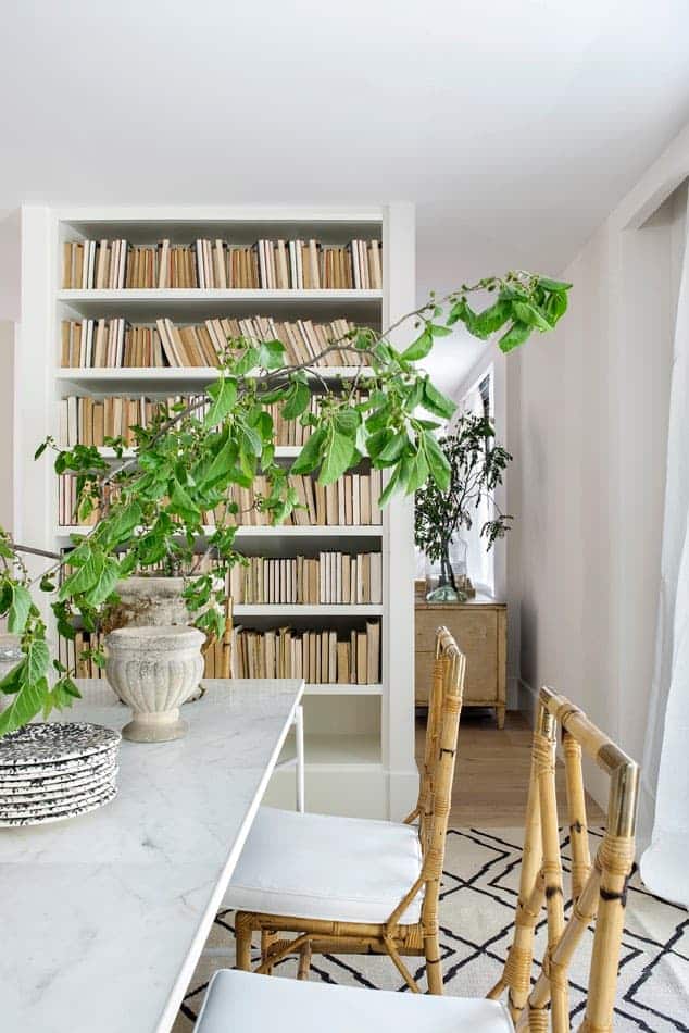 Estudio María Santos Reforma integral y decoración de vivienda minimalista Madrid comedor en tonos blancos con sillas de mimbre y biblioteca